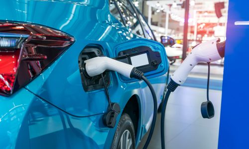 Electric car charging on parking lot with electric car charging station.